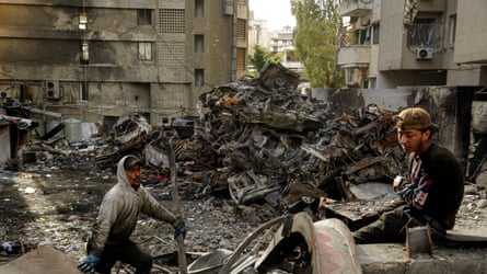 Men collecting scrap adjacent scores of burned cars astatine nan tract of an Israeli airstrike successful Beirut.