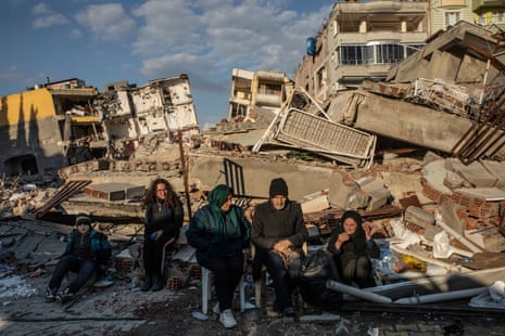A displaced family in Samandağ sitting in front of the debris of their house after the earthquake.