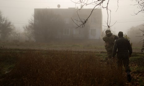 A Ukrainian serviceman walks with a chaplain on a street in a village near the newly recaptured city of Shihurivka.
