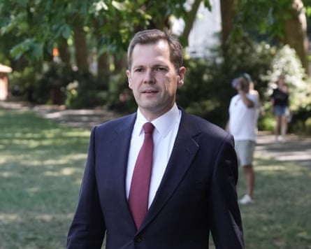 Robert Jenrick in suit walking in a park