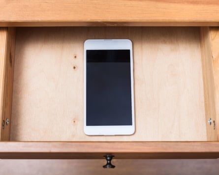 Above view of mobile phone in open drawer of nightstand