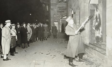 Civilians watch a Nazi officer vandalise Jewish property, most likely in Fürth, outside Nuremberg.