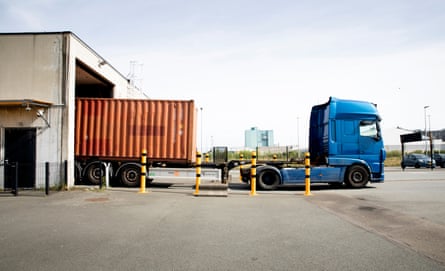 A blue lorry towing an orange shipping container leaves the scanning tunnel.
