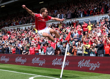 Sam Smith of Wrexham celebrates scoring his team's second goal with a flying kick at the corner flag.