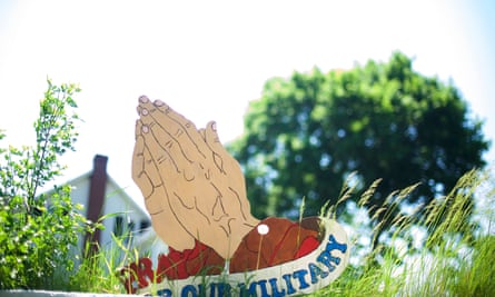 A wooden sign of praying hands for the military in Ackermanville.