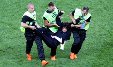 A woman is removed from the pitch during the World Cup final between France and Croatia.