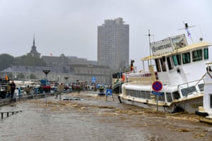 Liege, Belgium: Members of the public stand next to a damaged boat after flooding in the city.