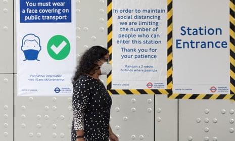 A woman wearing a face mask walks into an underground station in London