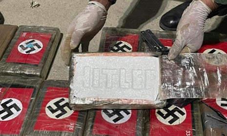 Photograph from Peruvian anti-drug police shows an officer with blocks of cocaine marked with the Nazi flag and stamped ‘Hitler’