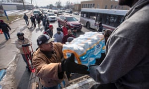 Volunteers unload gallons and cases of bottled water in front of a Flint, Michigan community center.
