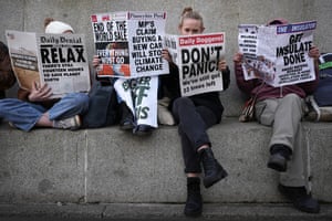 People sitting reading mock newspapers saying