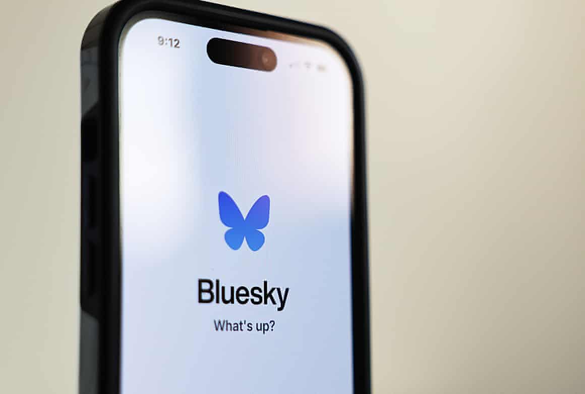 Bluesky logo of a blue butterfly on a phone screen.