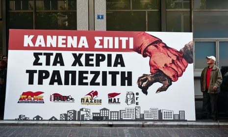 ‘A protester stands by a banner reading ‘No house in the hands of bankers’ in Athens.