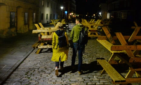 A couple walk through upturned pub seating in King Street in Bristol, England. 