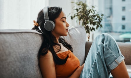 Posed by model Listening on headphones at home Shot of a young woman using headphones while relaxing on the sofa at home