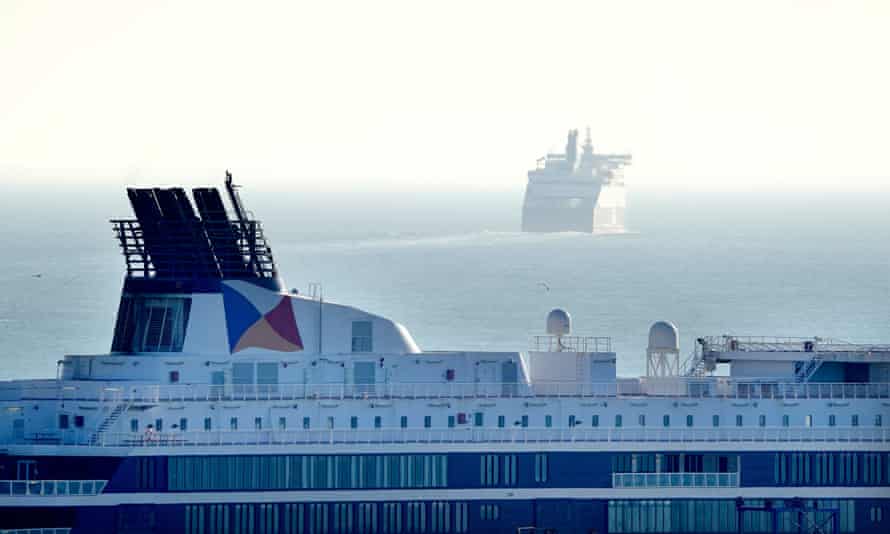 Close up of a modern ferry’s superstructure with the P&O flag visible on the funnel. In the background another ferry is making its way out to sea, in a haze