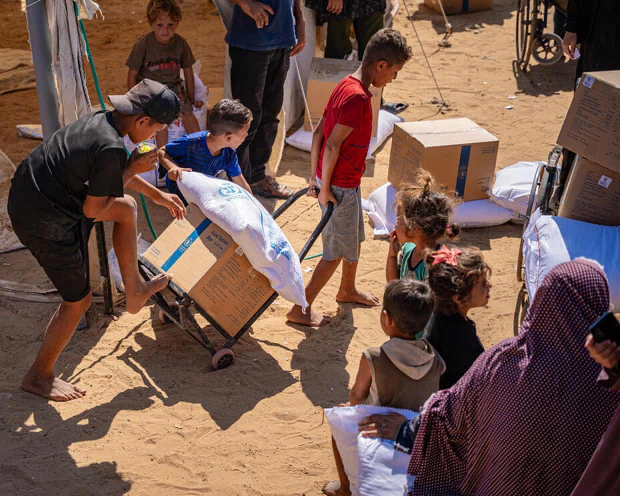 Children pulling a food parcels and sack of flour on a handcart