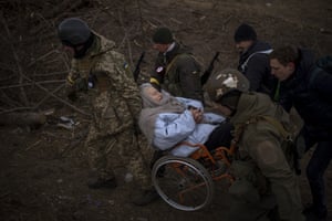 Soldiers help an elderly woman in a wheelchair as they evacuate the city