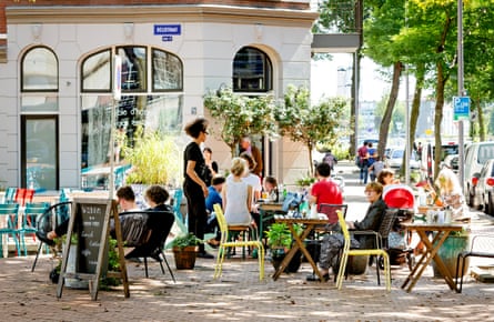A square with outdoor cafe seating in the shade of trees