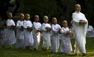 A Buddhist nun walks with novice nuns to receive food from people during the Songkran Festival at the Sathira-Dhammasathan Buddhist meditation centre