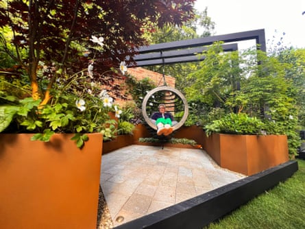 Donnelly sat in circular hanging seat amid paced garden