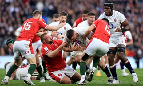 Tomas Francis of Wales (centre left, on ground) and Owen Watkin (No 13) of Wales challenge the England lock Charlie Ewels
