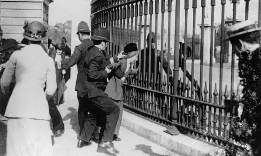 A police officer tries to remove a Suffragette from the railings outside Buckingham Palace, during a demonstration in London.