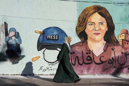 A woman walks past a mural of slain journalist Shireen Abu Akleh