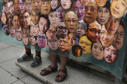 Two pairs of feet stick out from beneath a banner covered with headshots of men and women