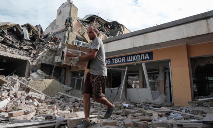 Anton, a teacher, carries out surviving items from his school destroyed as a result of a shelling in Bakhmut, Donetsk region.