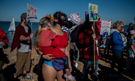 A woman holds her daughter while wearing a gas mask on Tankerton beach, Whitstable during a protest against sewage discharges by Southern Water on 9 October.