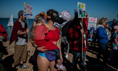 A woman holds her daughter whilst wearing a gas mask on Tankerton beach during a protest against sewage discharges by Southern Water on 9 October 2022.