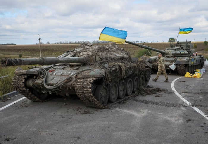 Two Russian tanks with Ukrainian flags flying over them