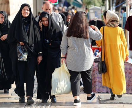 Veiled Iranian women pass by a bareheaded woman in Tehran on a street in Tehran