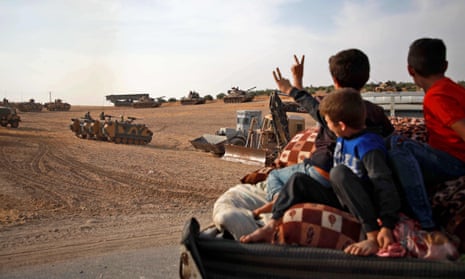 Syrian Arab civilians flash the victory sign as Turkish armoured personnel carriers and US-made M60 tanks gather in the village of Qirata on the outskirts of Manbij