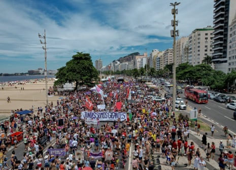 A large protest on a street next to a beach
