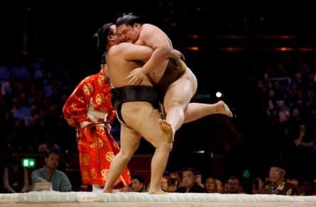 Oho kicks his feet as he is picked up and carried out of the ring by Kirishima
