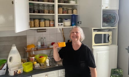 Woman holds orange block in front of kitchen worktop and cupboards