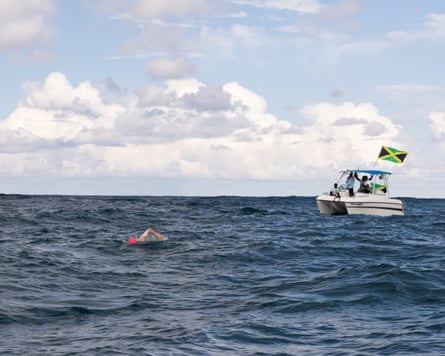 Eva Buzo swims in open ocean near a support boat flying the Jamaican flag