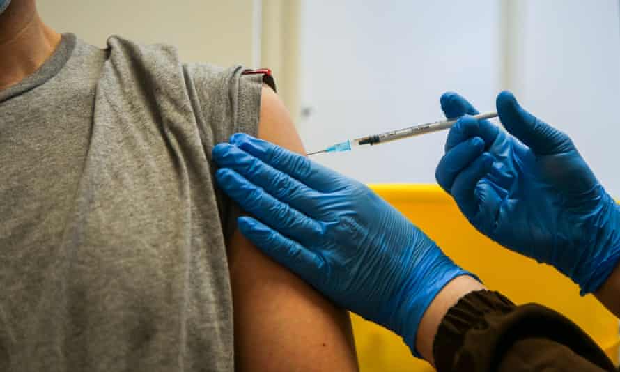 A vaccinator administers the Pfizer jab to a man at a vaccination centre in London