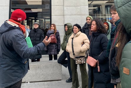 Kwame Ondo speaks with a group of a dozen people outside a building