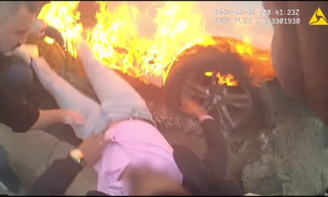 This body camera image from 27 January shows a police officer and barber on vacation saving an unconscious driver of a burning car in Las Vegas.