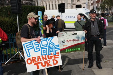 A man holding a sign reading 'Feck off orange turd'