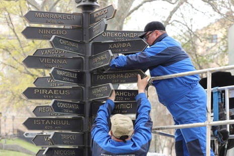 Service workers dismantle plates bearing the names of Russian cities from a decorative street sign indicating directions and distances in Odessa earlier this month.