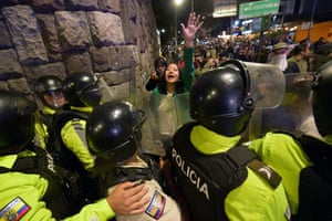 A woman holds up a hand in front of a row of police officers in hi-vis riot gear
