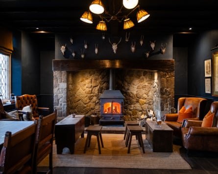 A pub interior with comfy sofas, tables, a wood burner and animal skulls above the fireplace
