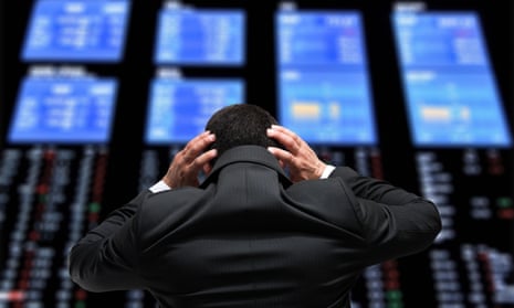 Businessman holds his head as he looks at the stock exchange screens
