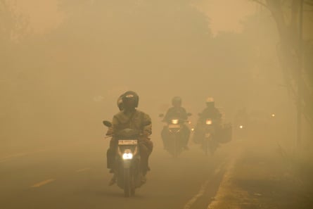 Motorcyclists ride through smoke haze