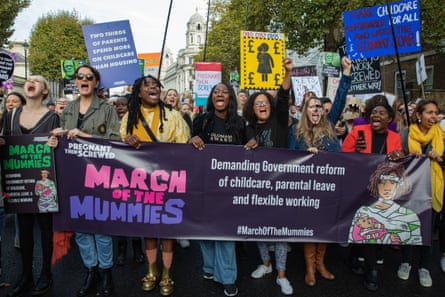 A crowd of people, mostly women, walk behind banners or holding placards.