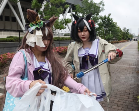Women in costume collecting litter with tongs